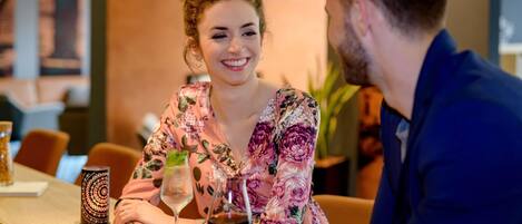 A person sitting at a table with a glass of red wine and a decorative candle.