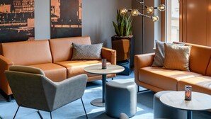 Un espacio lounge moderno con sofás de cuero, una mesa de centro redonda y una lámpara de techo original.