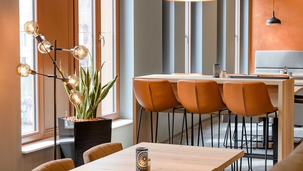 Un comedor moderno con una mesa de madera, sillas de cuero y una lámpara colgante.