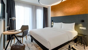 Una habitación de hotel moderna con una cama grande, un escritorio, una silla y una maleta en el suelo.