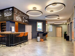 A modern bar area with a chalkboard wall, a reception desk, and a seating area with chairs.