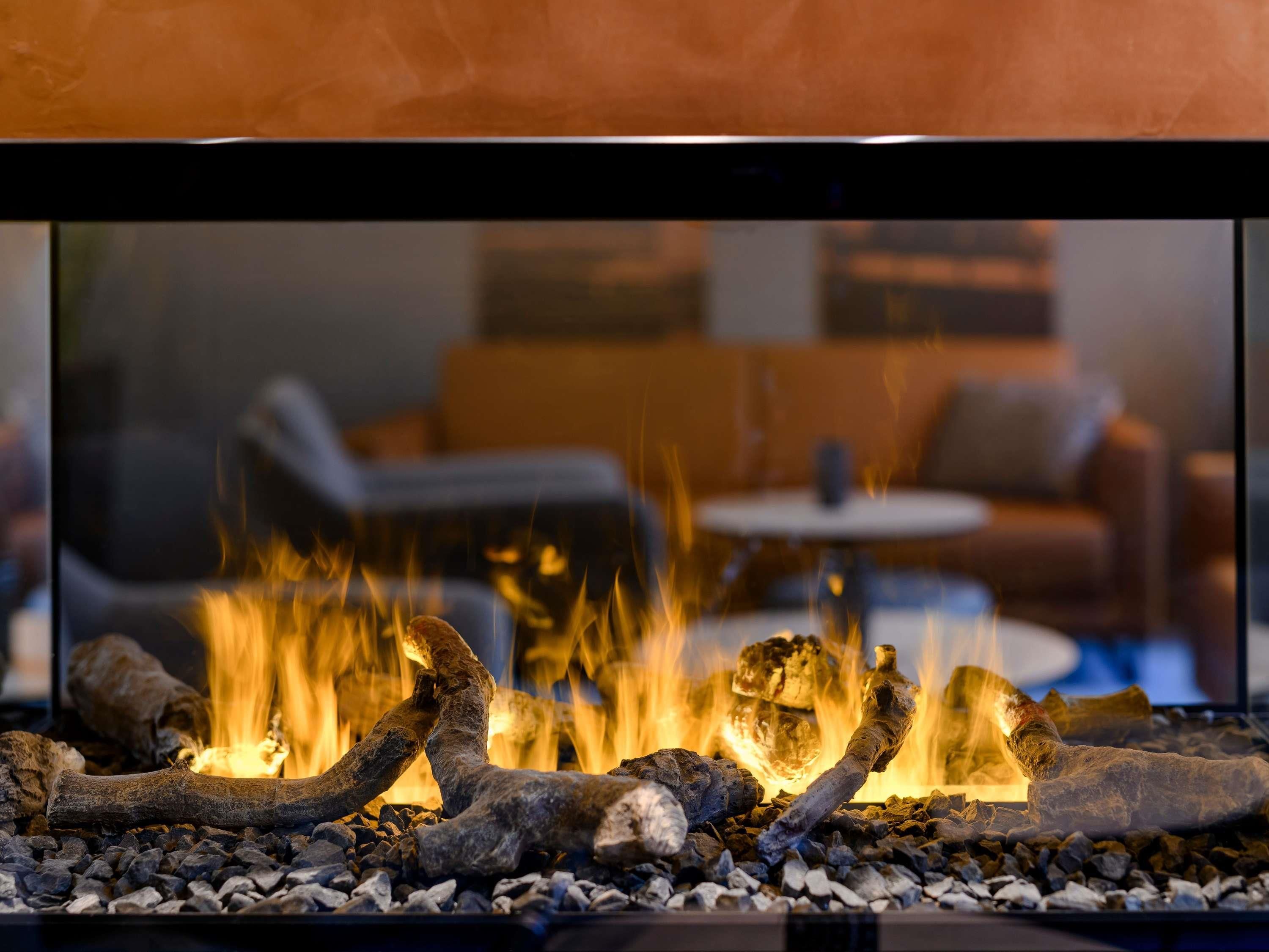 A fireplace with logs and burning embers, surrounded by a bed of rocks.