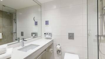 Une salle de bain moderne avec un grand miroir, un lavabo, des toilettes et un espace douche.