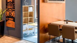 Un comedor moderno con una mesa de madera, sillas marrones y una estantería con un cojín blanco.