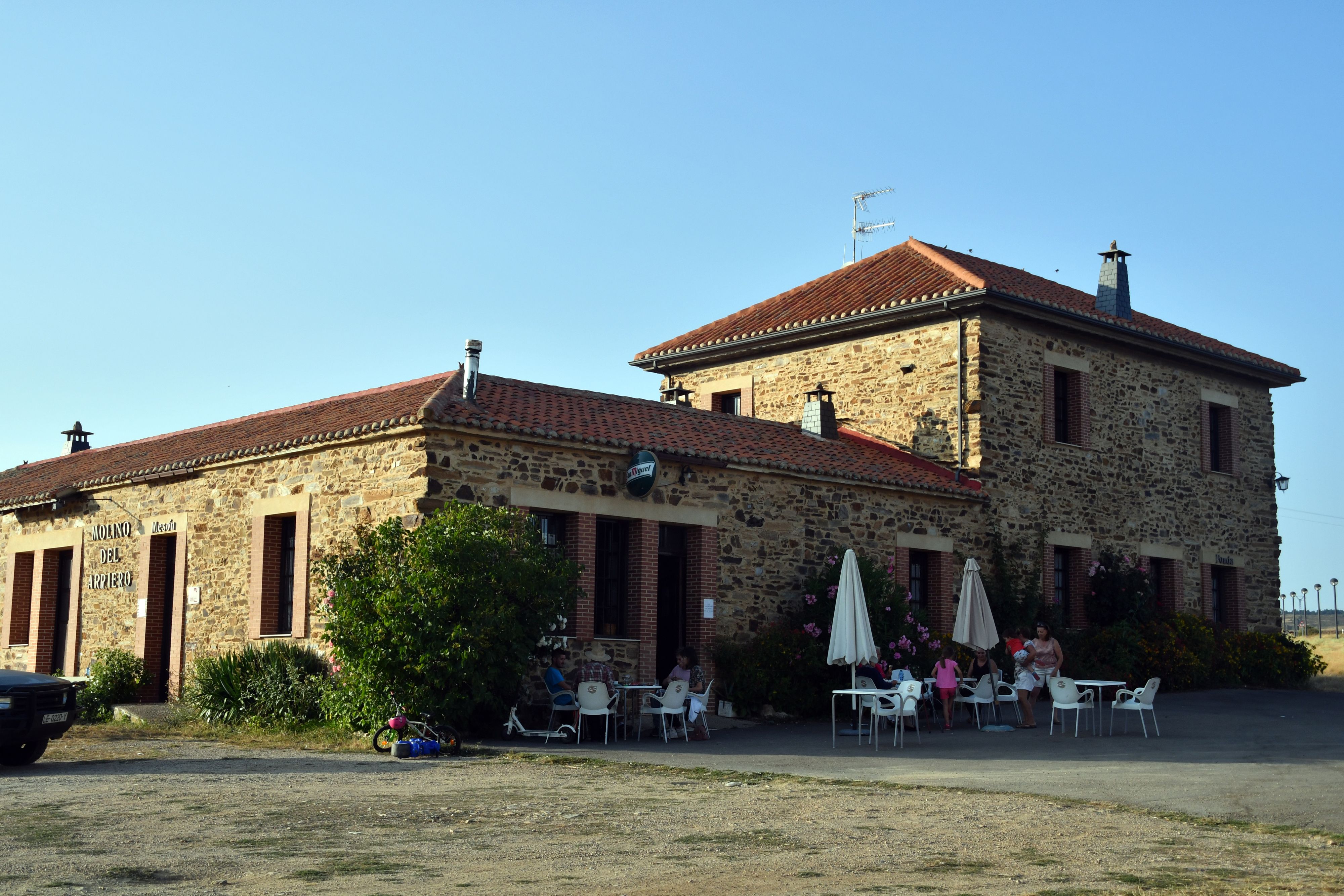Un edificio in pietra con tetto a tegole, area salotto all'aperto e un cartello che indica un ristorante.