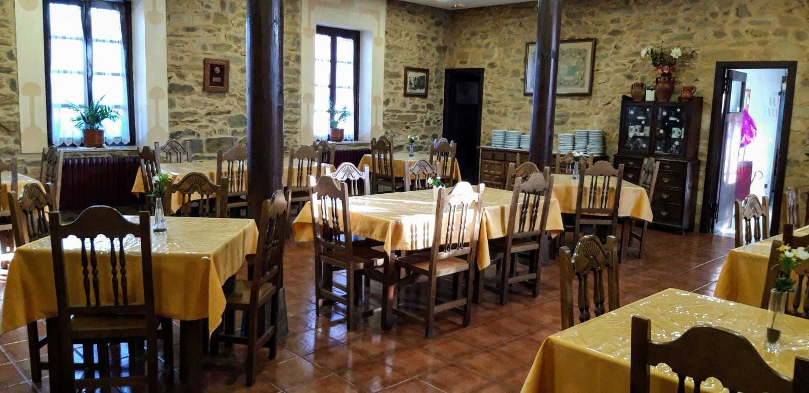 A dining area with multiple tables and chairs, stone walls, and a rustic interior.