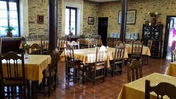 A dining area with multiple tables and chairs, stone walls, and a rustic interior.