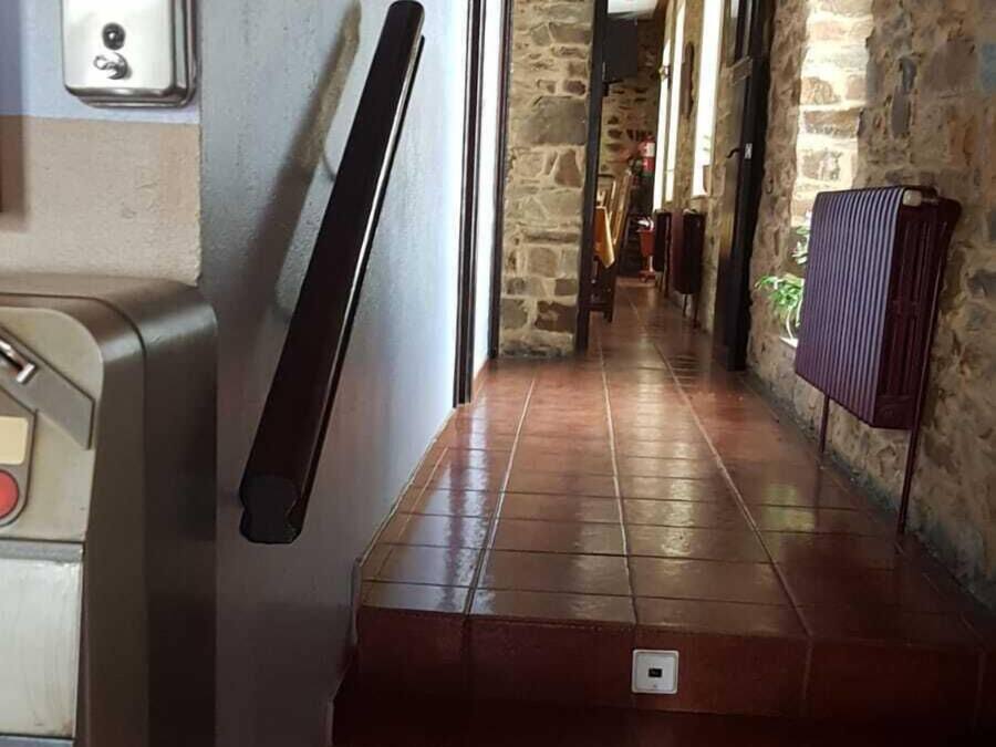 A staircase with a handrail, a stone wall, and a sign that reads "Comedor".