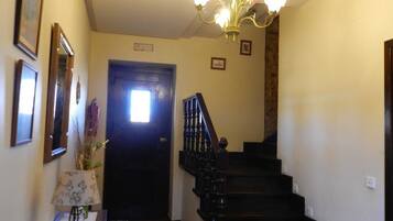 Una escalera con barandilla negra y un candelabro colgando.