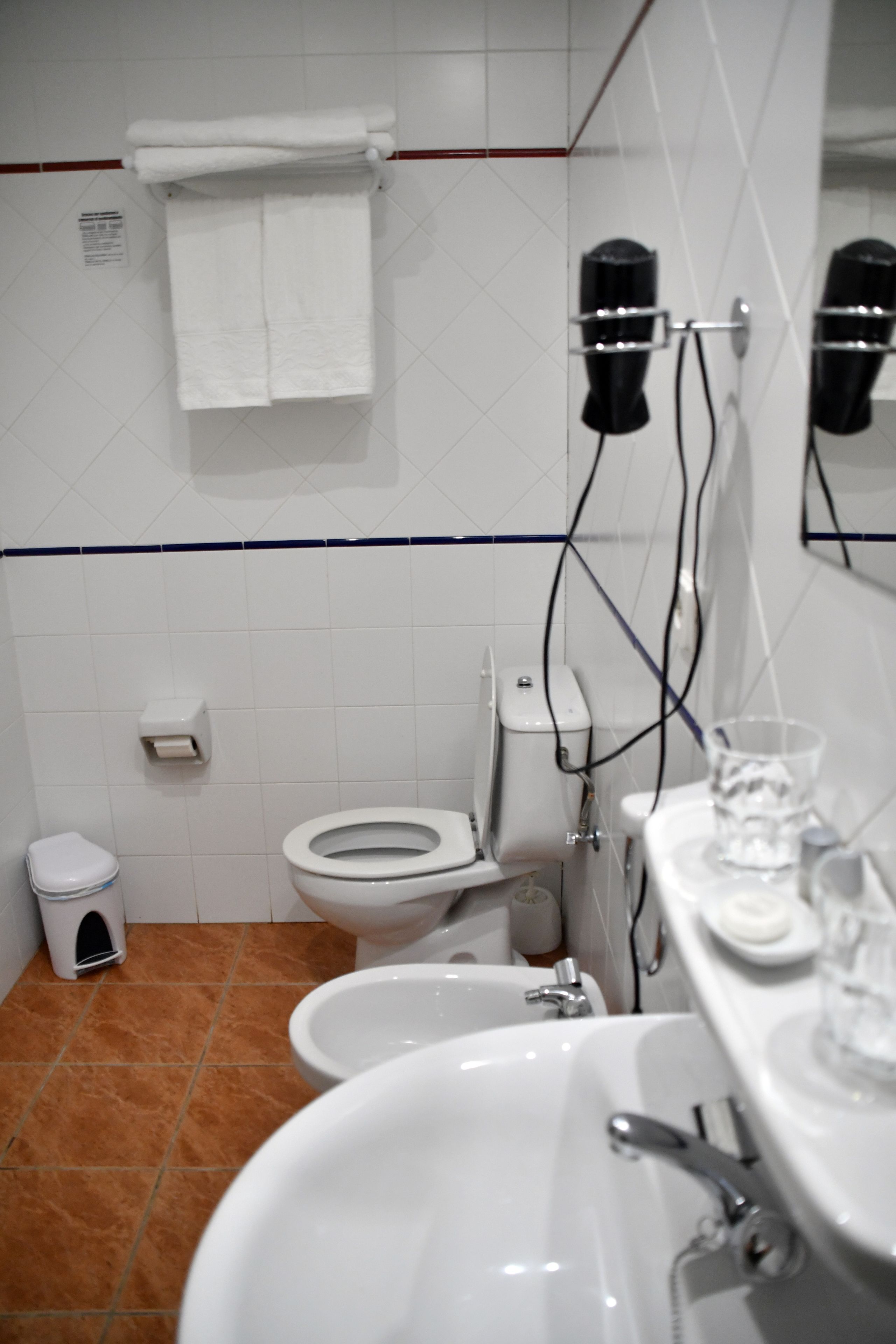 A bathroom with a toilet, bidet, sink, and towel rack.