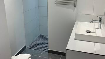 A modern bathroom with a shower, toilet, and sink.
