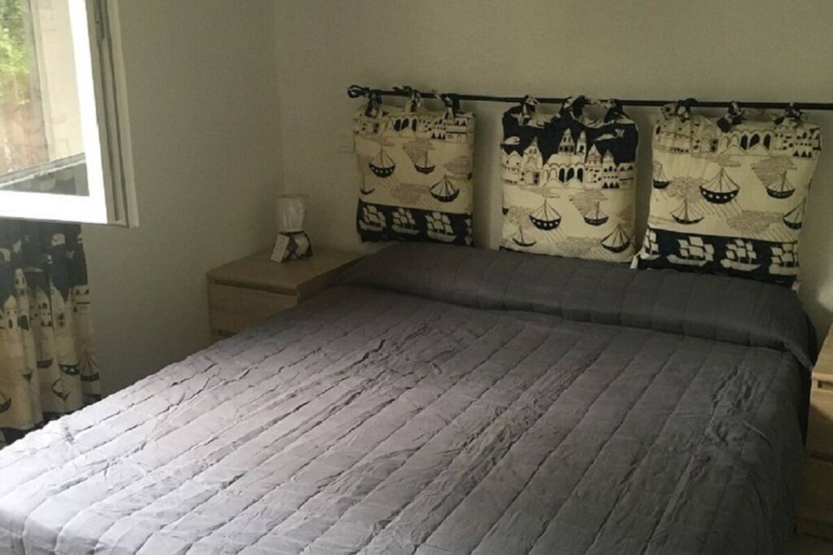 Une chambre à coucher comprenant un lit, une table de chevet et deux coussins décoratifs aux motifs marins.