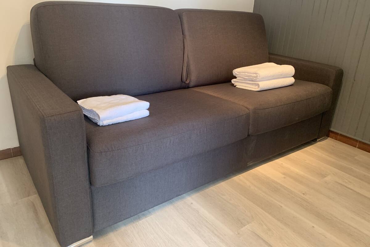 Un canapé gris sur lequel sont posés deux serviettes blanches pliées.