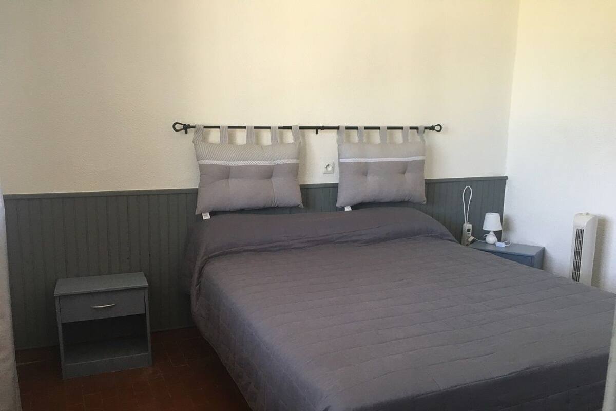 Une chambre à coucher avec un lit, deux oreillers, une table de chevet, une lampe et un radiateur.