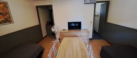 Ein Wohnzimmer mit einem Holztisch, zwei Sofas, einem Fernseher und einem Ventilator.