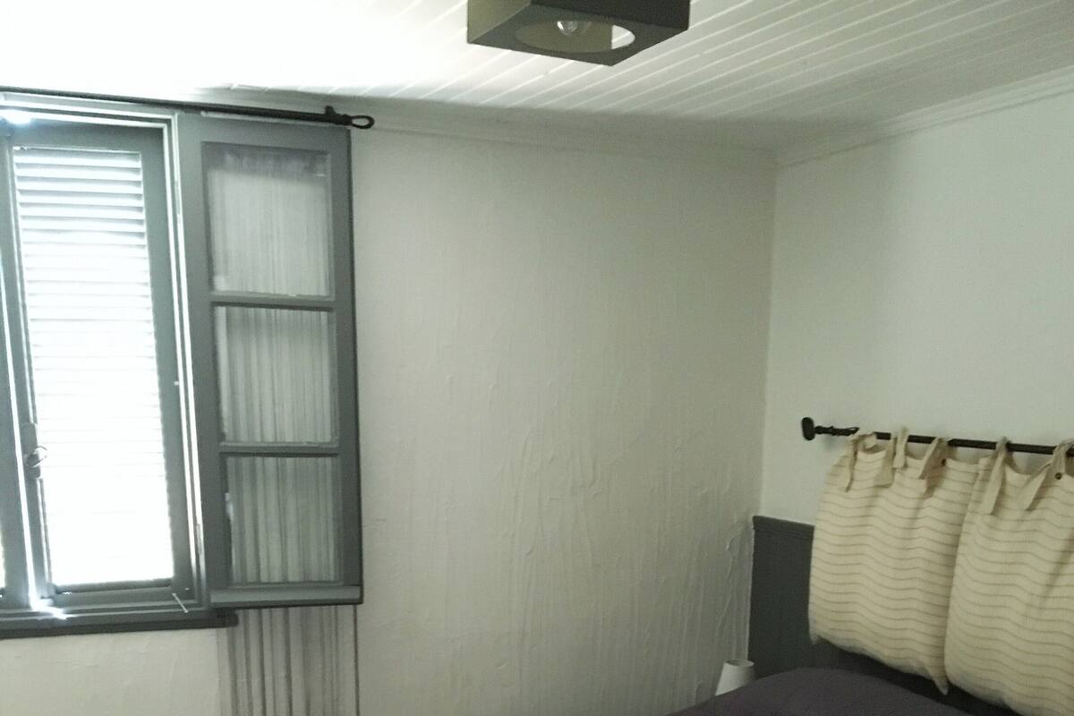 Un lit bien fait, recouvert d’une couvre-lit de couleur foncée, avec deux serviettes blanches pliées posées dessus.