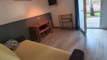 A room with a bed, a desk, a chair, a TV, and a sliding glass door to the outside.