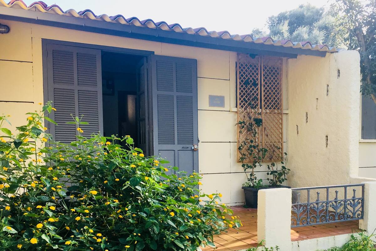 Une maison avec deux portes ouvertes, un balcon doté d’une balustrade et un pot de fleurs.