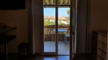 Una habitación con puerta de vidrio corredera que da a un patio exterior con mesa y sillas.