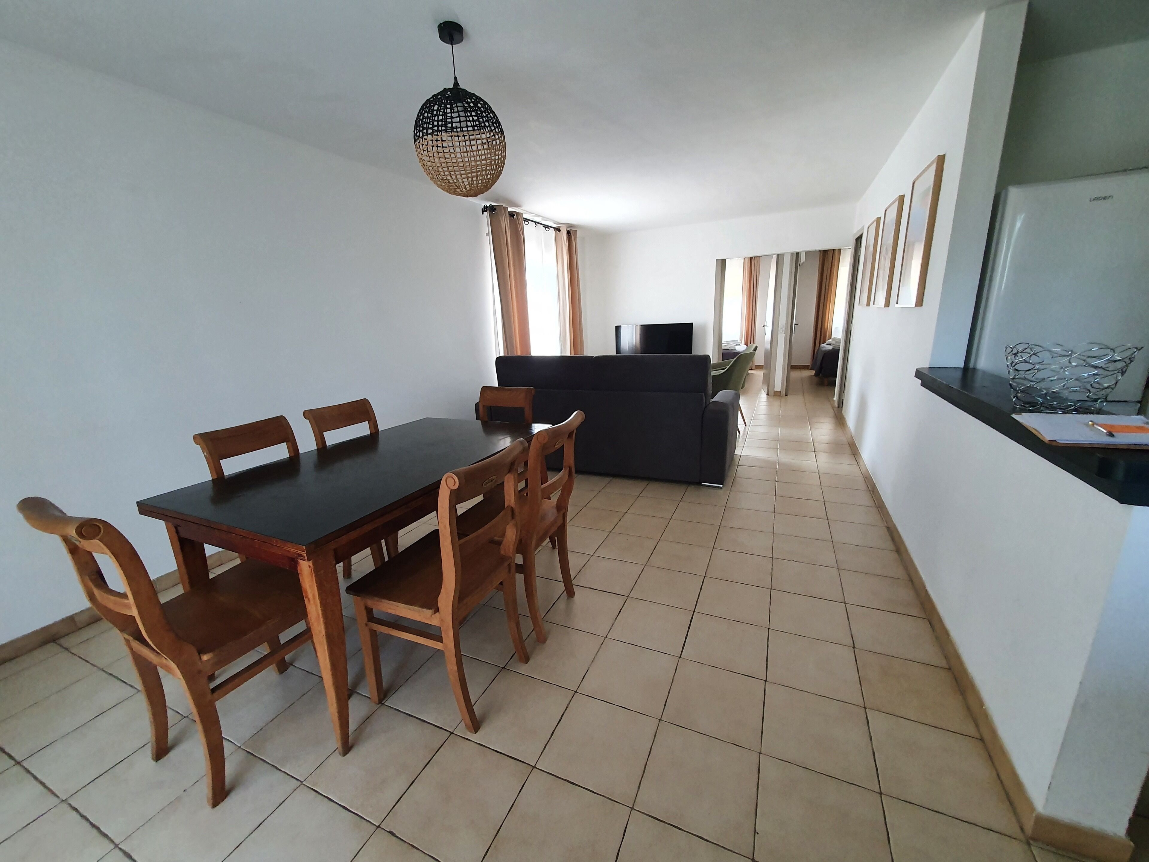 A spacious living area with a dining table, chairs, a sofa, and a TV.
