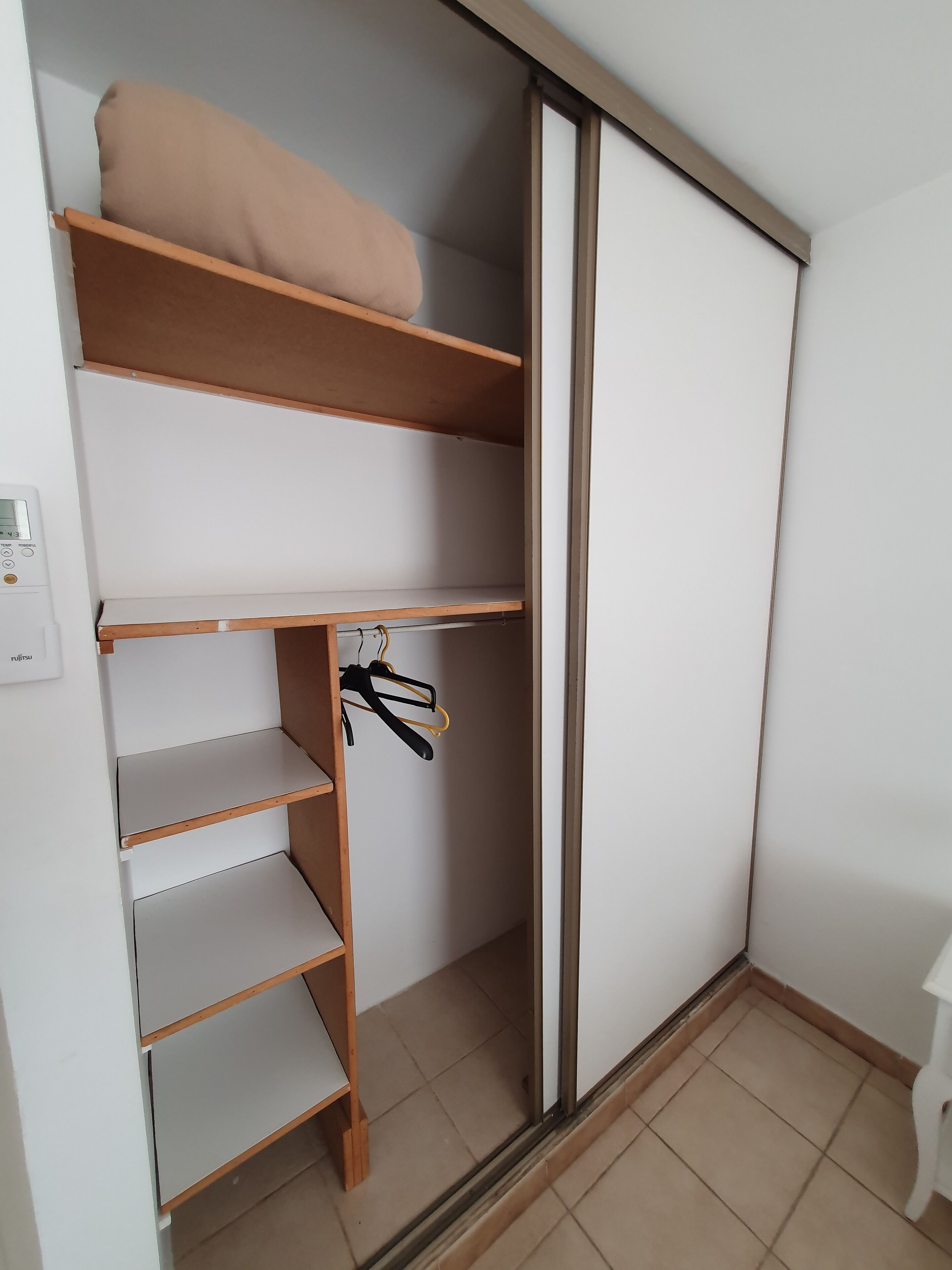 A walk-in closet with wooden shelves and a sliding door closet.