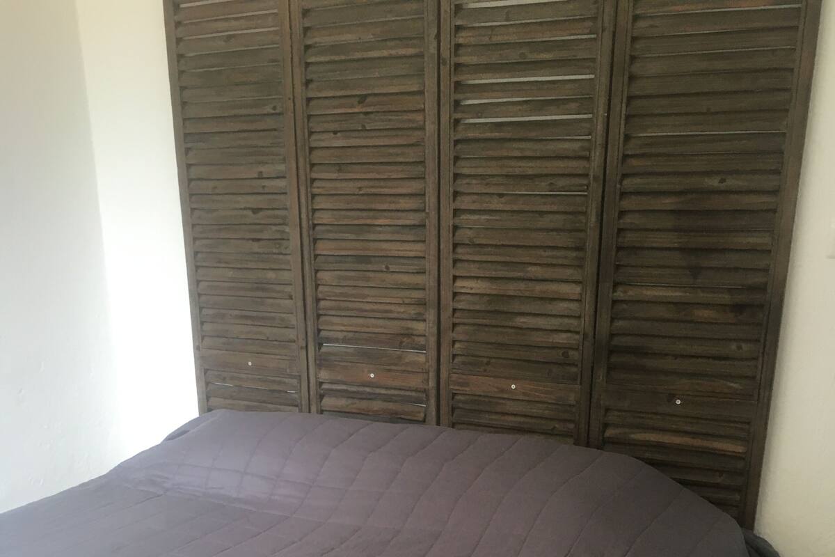 Une chambre à coucher avec un grand lit, une tête de lit en bois et un sol carrelé.