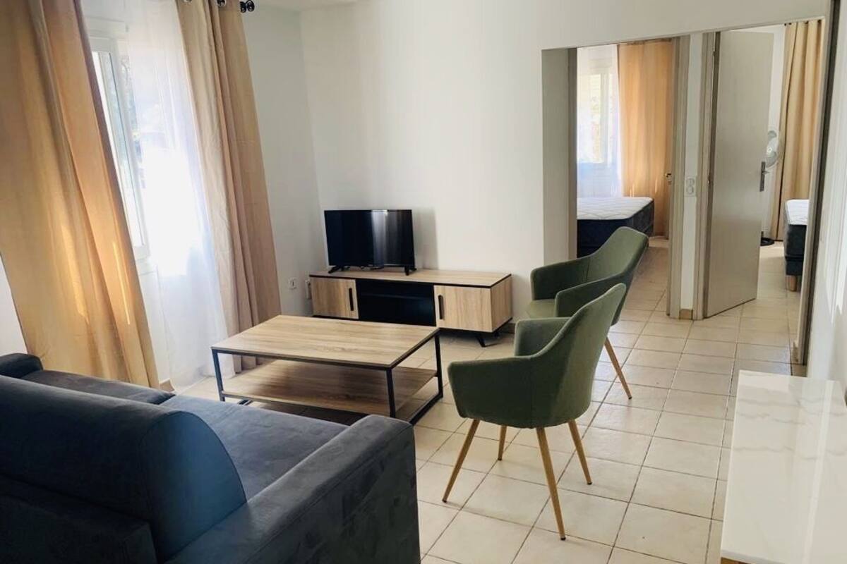 Un salon moderne comprenant un canapé, une table basse, un téléviseur et un coin repas avec des chaises.