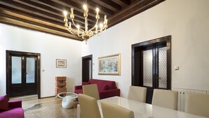 A spacious living room with a large dining table, red sofa, and a chandelier. - San Marco Schiavoni Apartments (Venice)