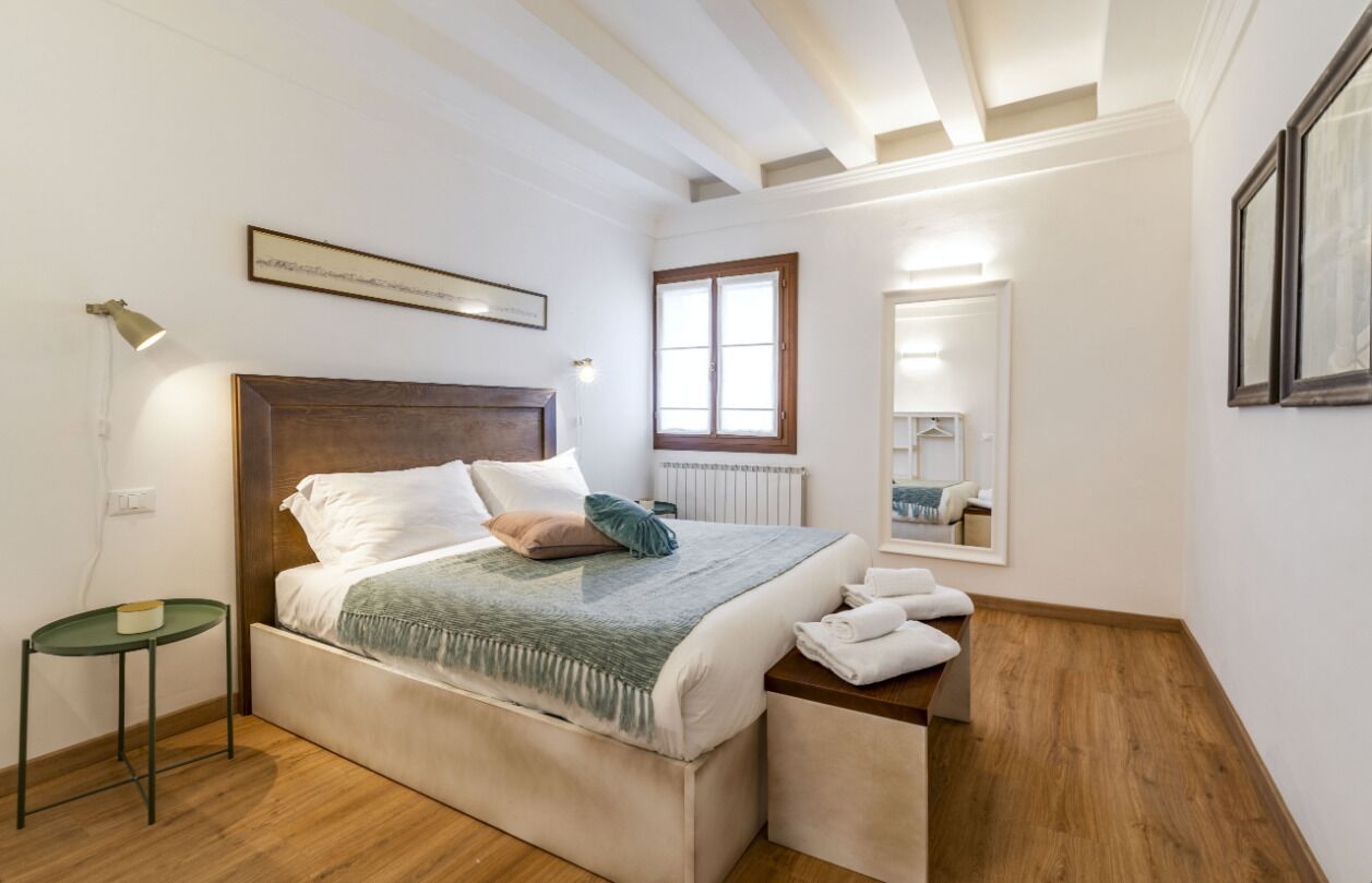 A bedroom with a bed, bedside table, and a mirror.