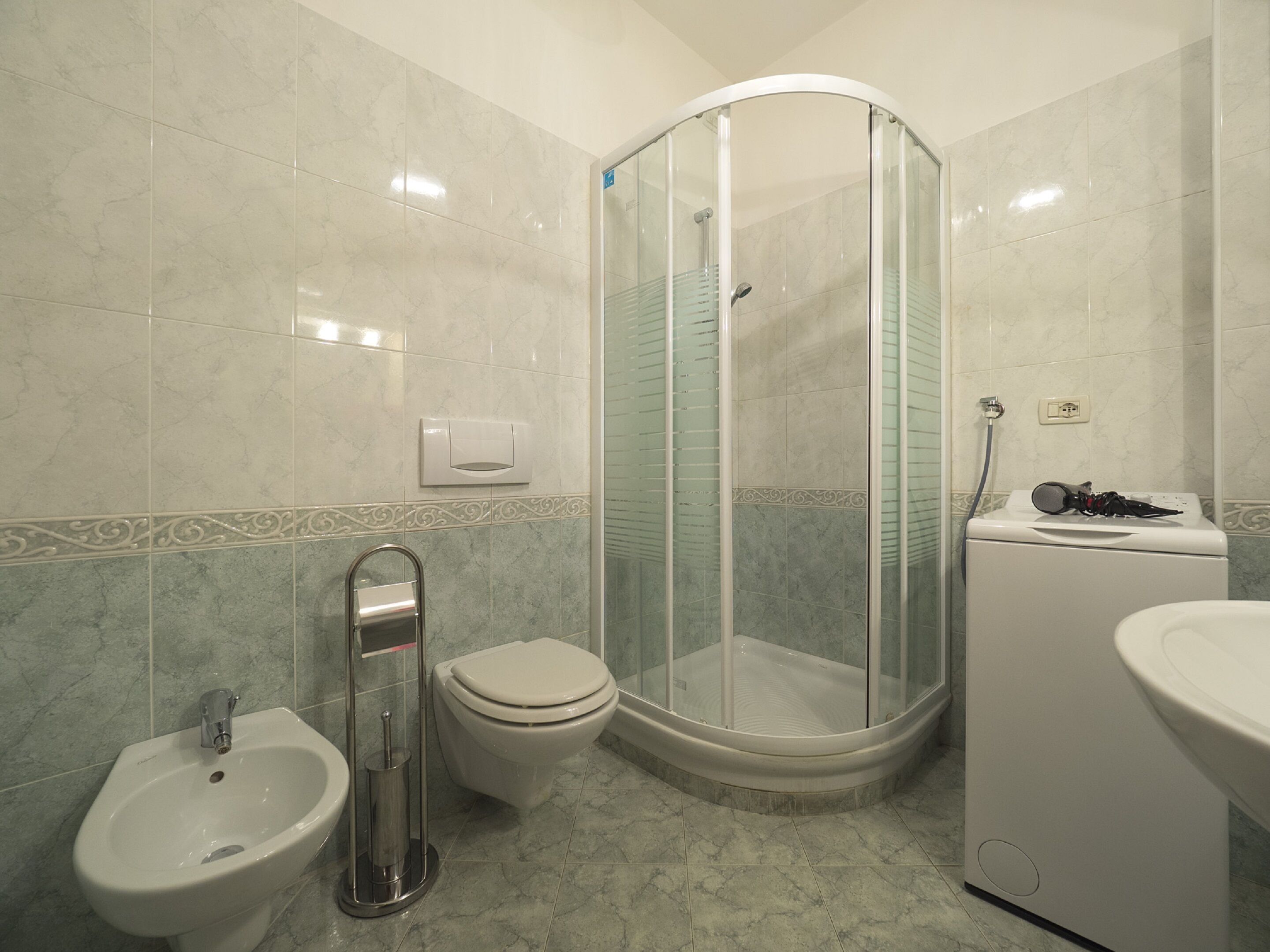 Un bagno con box doccia, un water, un bidet e un lavandino.