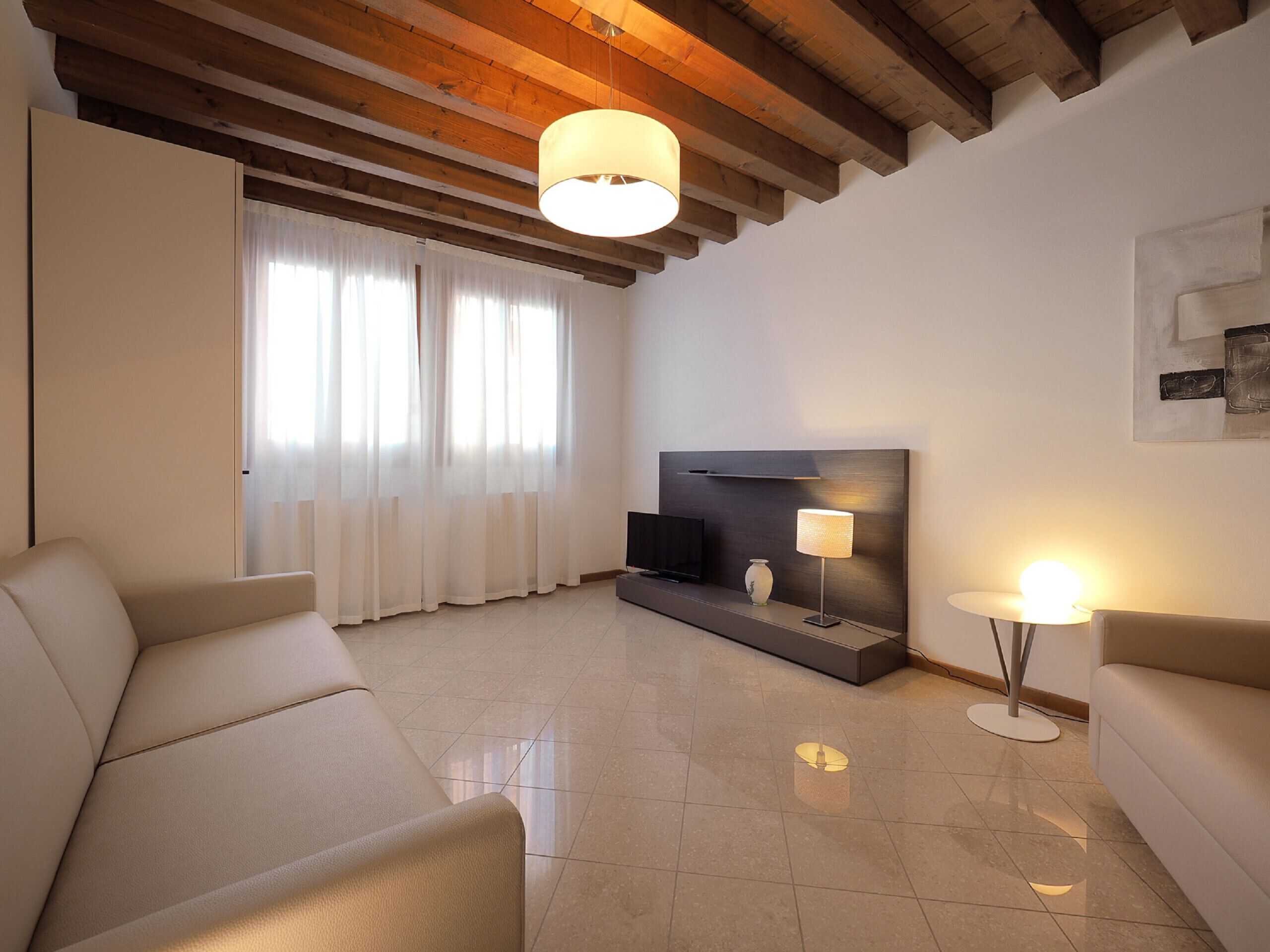 A modern living room with a sofa, a TV, and a lamp.