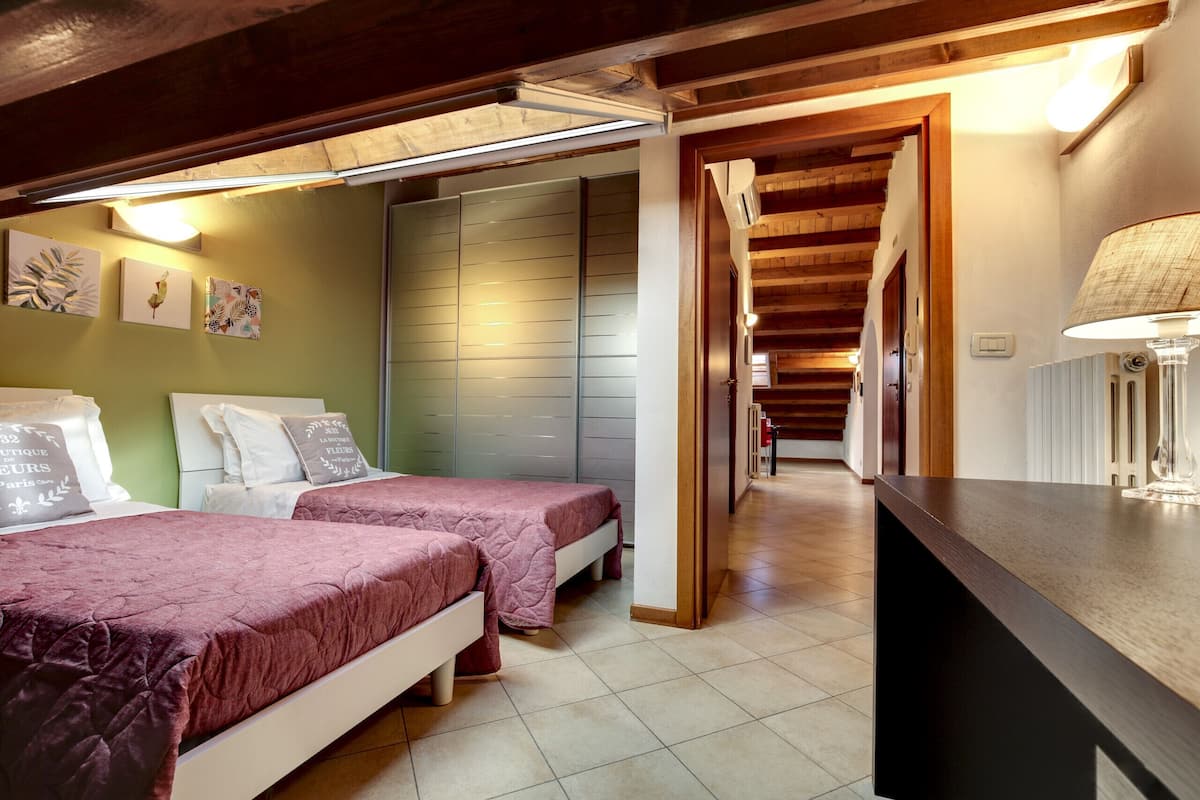 A bedroom with two beds, a wooden ceiling, and a hallway leading to another room.