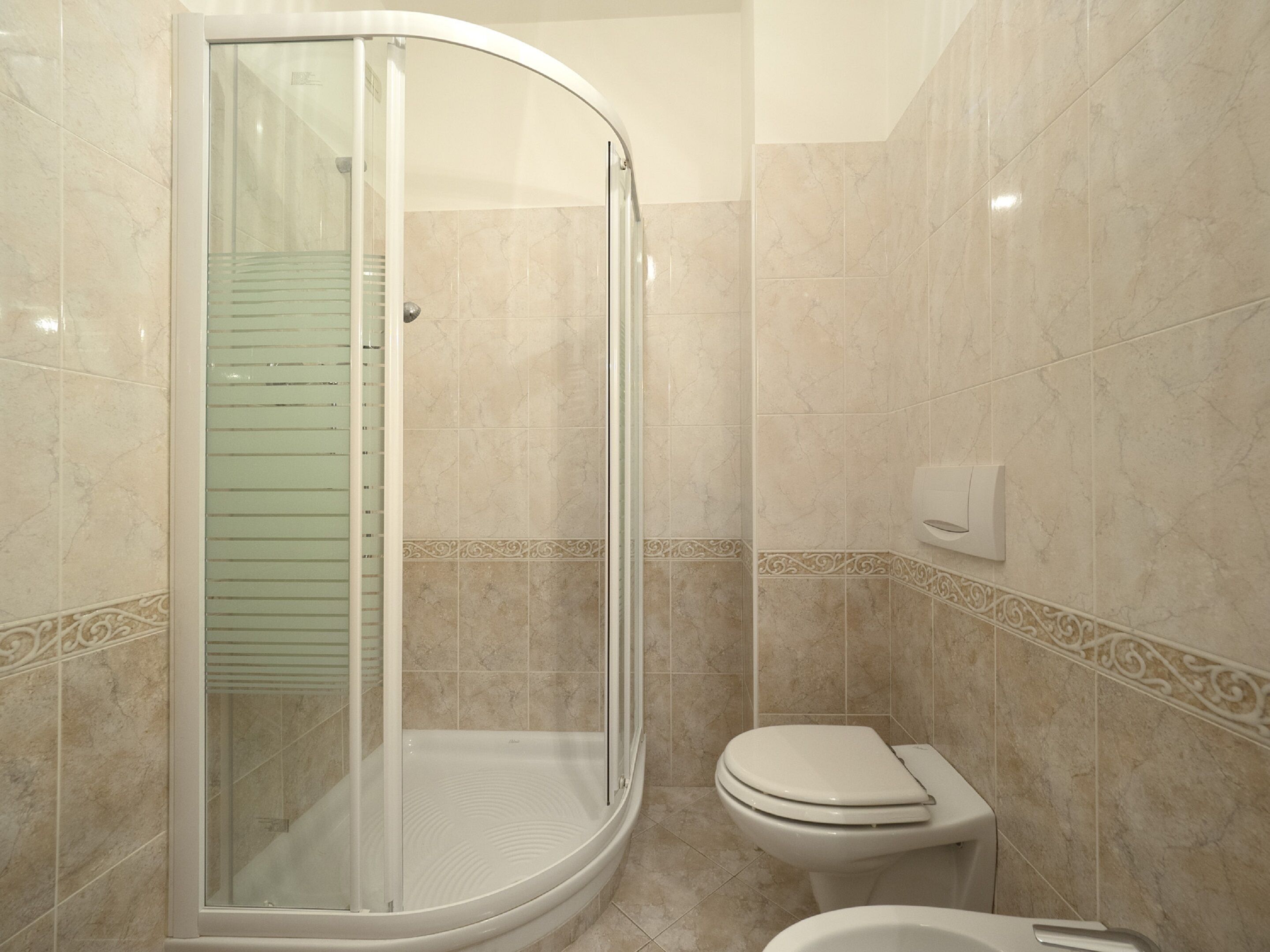 A bathroom with a glass-enclosed shower, a toilet, and a bidet.