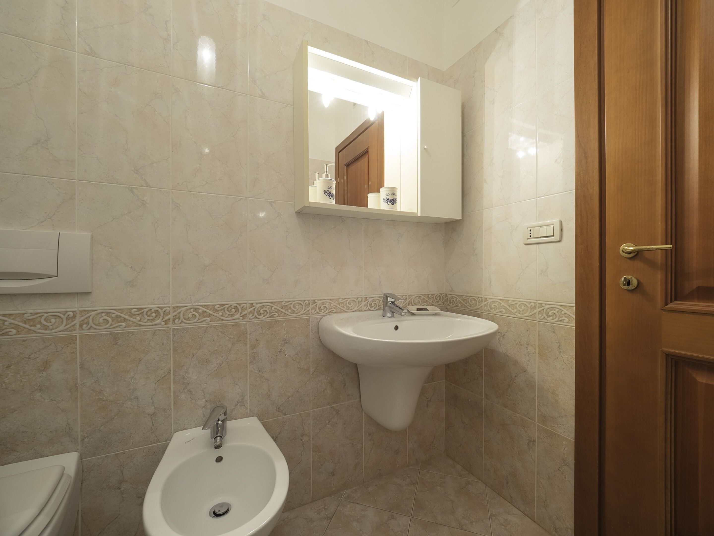 Un baño con lavamanos pedestal, espejo montado en la pared y un inodoro.