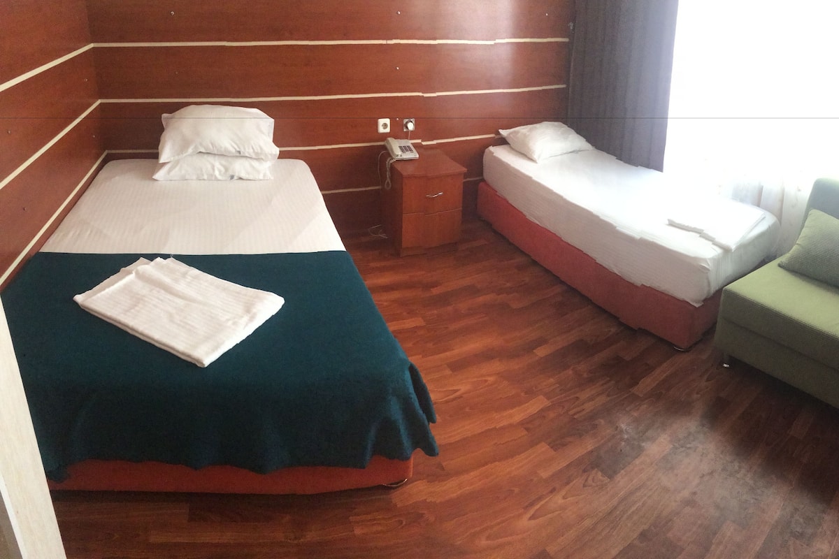 A hotel room with a bed, bedside table, and a green armchair.