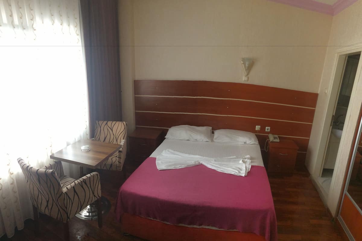 A hotel room with a bed, a desk, and a chair.