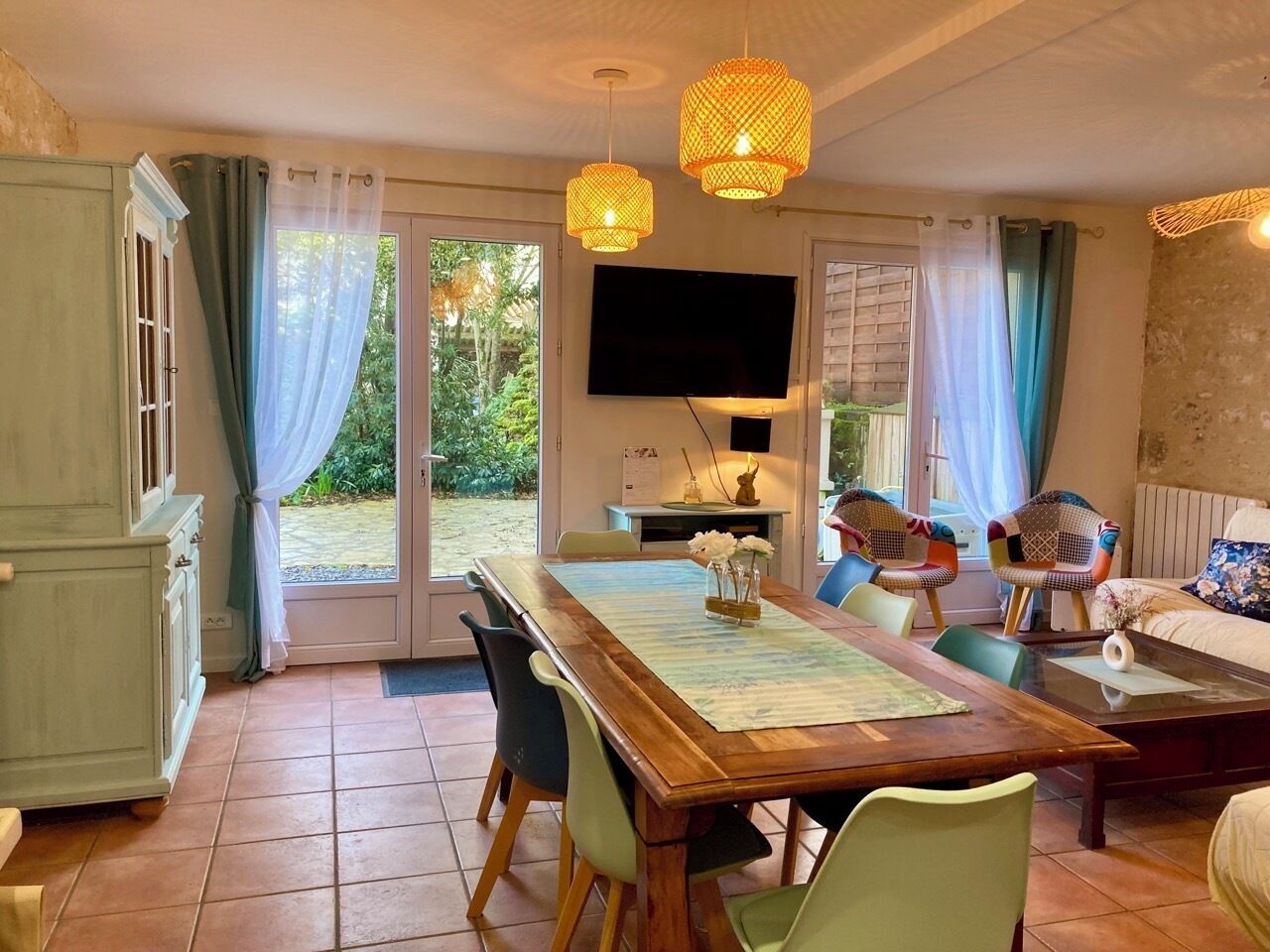 Un coin repas avec une table en bois, des chaises et un téléviseur fixé au mur.