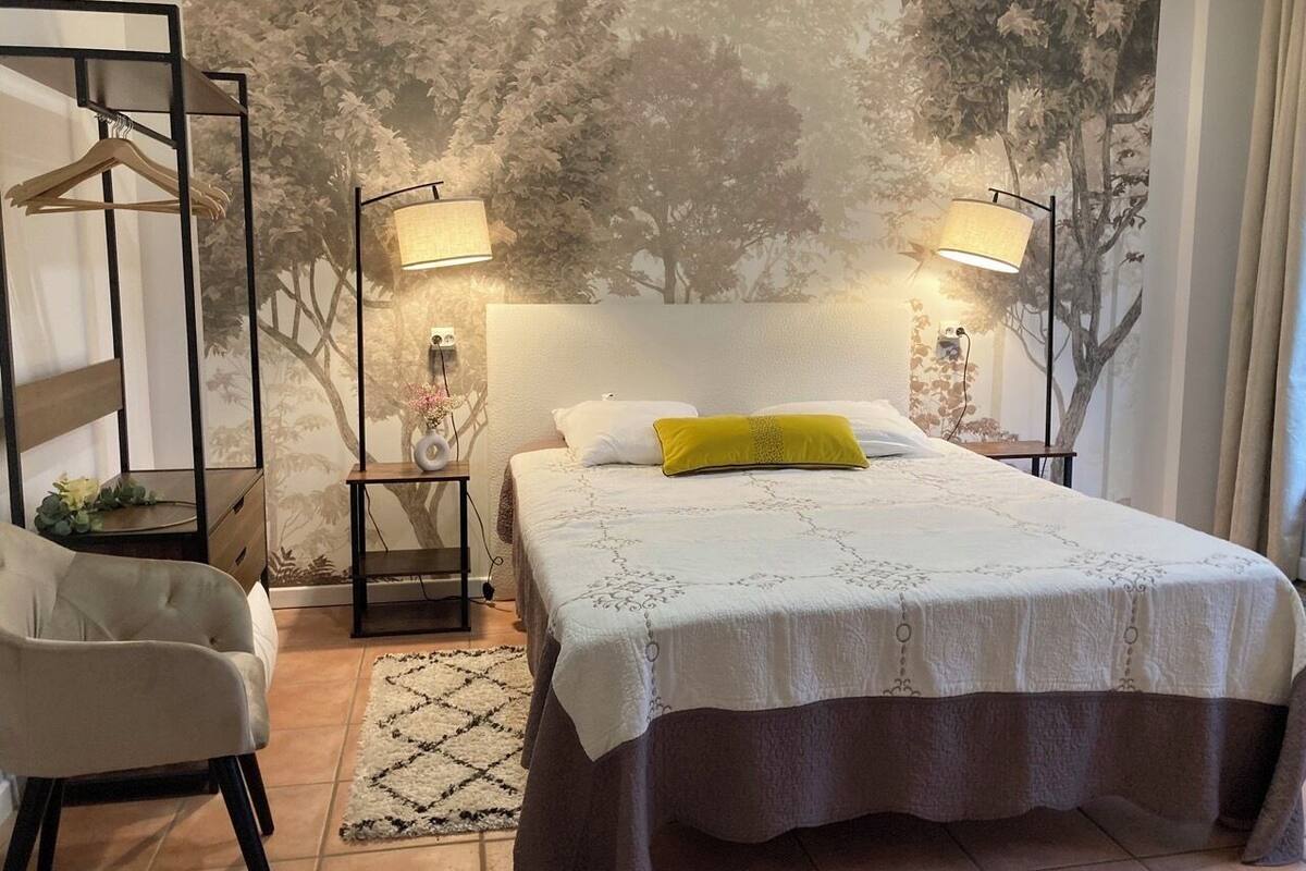 A bedroom with a bed, a chair, a nightstand, and a wall mural.