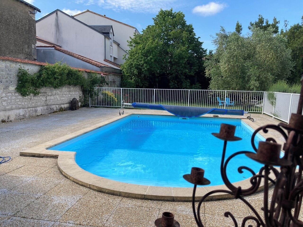 Une piscine rectangulaire entourée d’une clôture blanche.