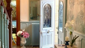 A hallway with a white door, a mirror, a radiator, and a vase of flowers. - Villa des roses (Luçon)