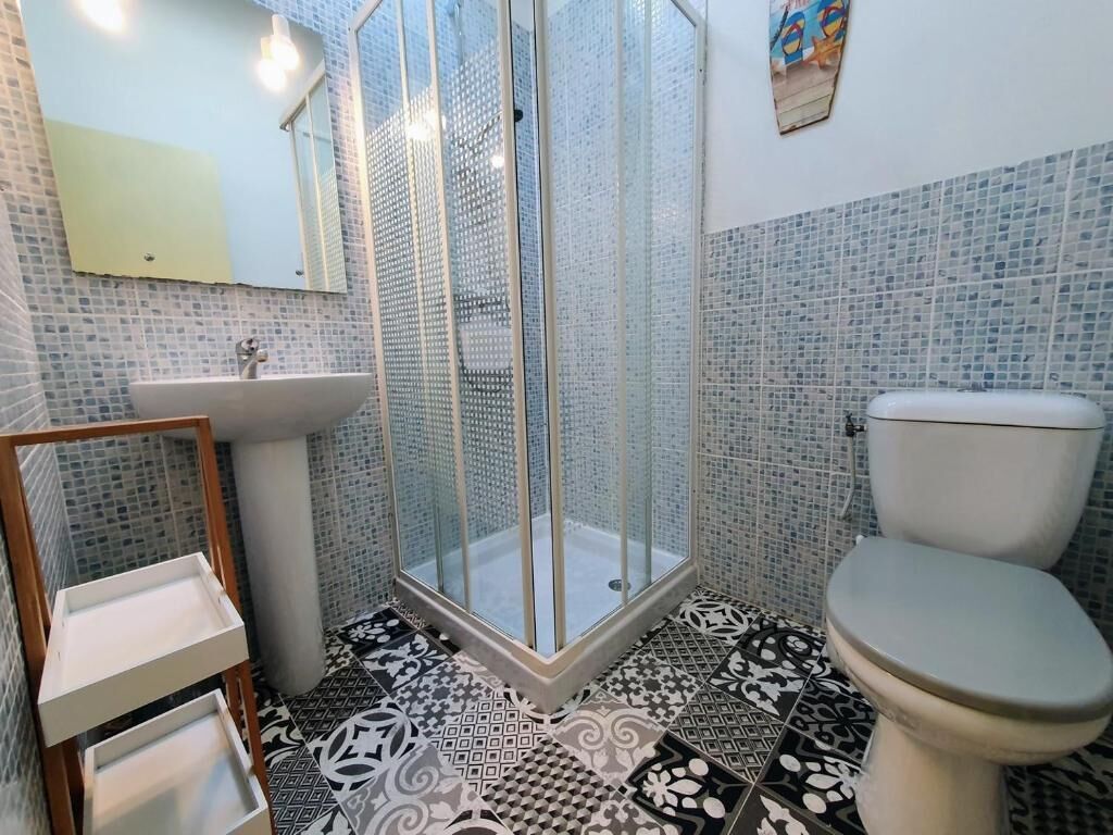 A bathroom with a glass-enclosed shower, a sink, and a toilet.