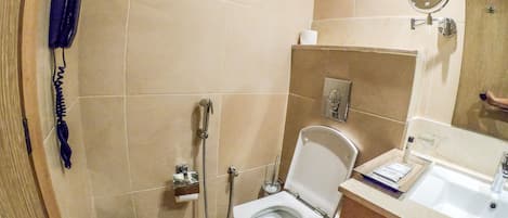 A bathroom with a toilet, a sink, a mirror, and a telephone.