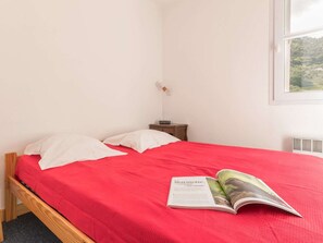 A room with a bed, a nightstand, and a window.