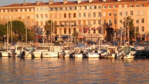 A marina with multiple boats docked, surrounded by multi-story buildings with balconies.