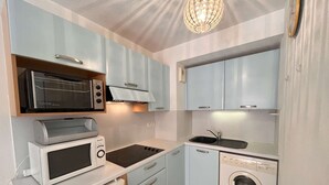 A compact kitchen with a microwave, toaster, stove, sink, and washing machine.