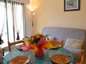 Uma mesa de jantar com um arranjo floral, um sofá e um quadro na parede.