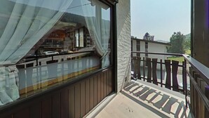 A balcony with a view of a street and buildings. - Sunny 2BR Mezzanine Apt with Mountain Views, Fireplace, Near Shops & Lifts, Sleeps 6 (Le Grand-Bornand)