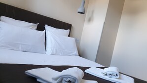 A neatly made bed with white linens and two rolled towels on a dark brown bedspread. - Le Bercail (Saint-Jean-de-Monts)