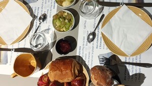 A table set with various dishes including bread, fruits, and a beverage. - Le Bercail (Saint-Jean-de-Monts)