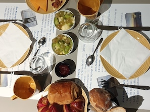 Uma mesa posta com diversos pratos, incluindo pão, frutas e uma bebida.